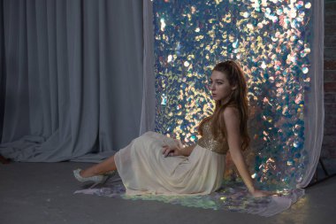 Parlak arka planda poz veren gece elbisesi içindeki muhteşem genç bayan. Parlak bir arka planda gece elbisesi giymiş bir kız.