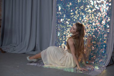 Parlak arka planda poz veren gece elbisesi içindeki muhteşem genç bayan. Parlak bir arka planda gece elbisesi giymiş bir kız.