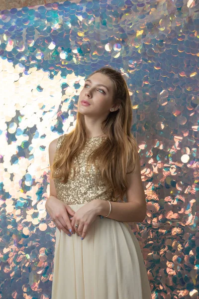 Parlak arka planda poz veren gece elbisesi içindeki muhteşem genç bayan. Parlak bir arka planda gece elbisesi giymiş bir kız.