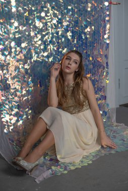 Parlak arka planda poz veren gece elbisesi içindeki muhteşem genç bayan. Parlak bir arka planda gece elbisesi giymiş bir kız.