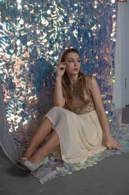 Parlak arka planda poz veren gece elbisesi içindeki muhteşem genç bayan. Parlak bir arka planda gece elbisesi giymiş bir kız.