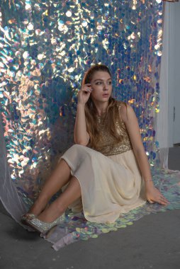 Parlak arka planda poz veren gece elbisesi içindeki muhteşem genç bayan. Parlak bir arka planda gece elbisesi giymiş bir kız.