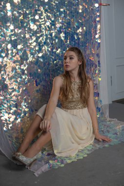 Parlak arka planda poz veren gece elbisesi içindeki muhteşem genç bayan. Parlak bir arka planda gece elbisesi giymiş bir kız.