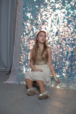 Parlak arka planda poz veren gece elbisesi içindeki muhteşem genç bayan. Parlak bir arka planda gece elbisesi giymiş bir kız.