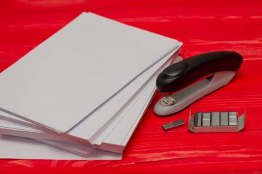 Kağıt dikişler için siyah ofis zımbası. Zımba ve zımba, ahşap bir masanın üzerinde kağıt parçaları..