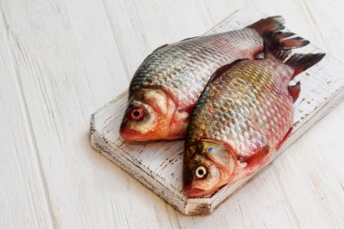 Taze balık. Beyaz ahşap arka planda çiğ balık. Masadaki beyaz ahşap mutfak tahtasındaki balıklar
