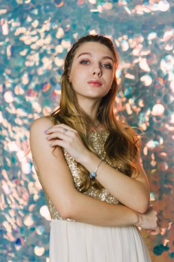 Parlak arka planda poz veren gece elbisesi içindeki muhteşem genç bayan. Parlak bir arka planda gece elbisesi giymiş bir kız.