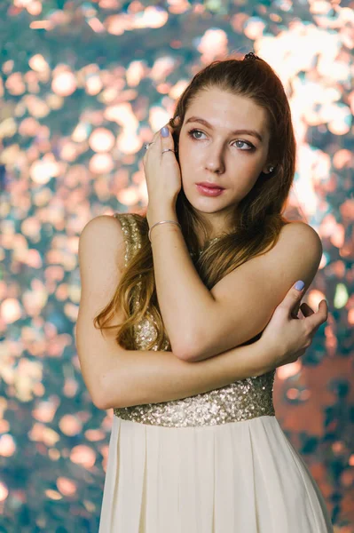 gorgeous young woman in evening dress posing over sparkling background. Girl in an evening dress on a shiny background