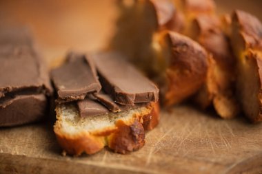 Doğal ahşap tahtalardan yapılmış hafif bir masanın üzerinde çikolatalı tereyağının yuvarlandığı bir tahta kesme tahtası var. Çikolatalı çörek.