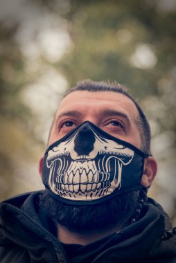 Kışlık elbiseli bir adam sokakta, yüzünde sağlık maskesi olan bir adam..