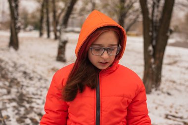 Parlak turuncu ceketli bir kız. Karlı havada turuncu ceketli bir kız. Kışın genç kız