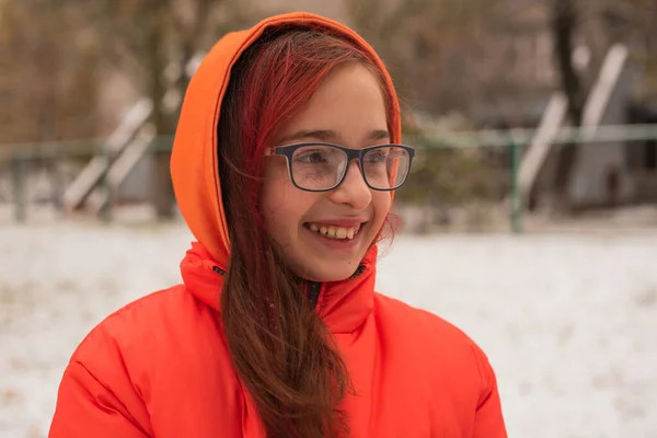 穿着鲜艳橙色保暖夹克的女孩 下雪天穿橙色夹克的女孩 冬天的少女 — 图库照片