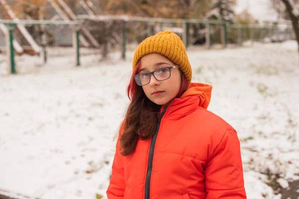 明るいオレンジの暖かいジャケットの女の子 雪の日にオレンジのジャケットの女の子 冬の十代の女の子 — ストック写真