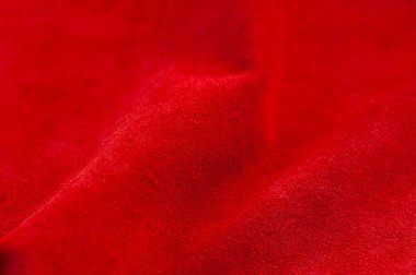 Süet kumaşın kırmızı mat arka planı, yakın plan. Pürüzsüz deri kadife desenli. Keçeli kumaş