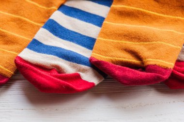 Ahşap arka planda örülmüş çizgili çoraplar. Ev yapımı tekstil ürünleri. Çorap, örgü