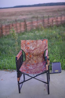 Balık tutma konsepti. Yeşil çimlerin üzerinde balıkçı sandalyesi. Doğada kamp sandalyesi