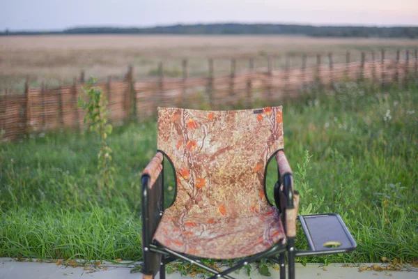 Fishing concept. Fishing chair on green grass. Camping chair in nature