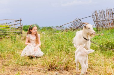Yazın açık havada küçük bir kızın portresi. Kız ve keçi.