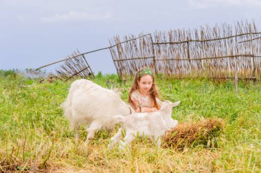 Yazın açık havada küçük bir kızın portresi. Kız ve keçi.