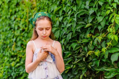 Yazın açık havada küçük bir kızın portresi. Kollarında küçük bir kedi yavrusu olan bir çocuk..