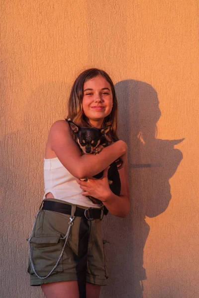 黄色の背景にヒップスターガールの肖像画 彼女の腕の中でChihuahuaと10代の女の子 — ストック写真