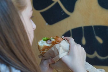 Burger yiyen bir genç. Hamburger yiyen genç bir kız. Fast food