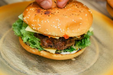 Hamburger pişirmek, hamburger yapmak, çöreklerle resimler, çiğ et, peynir ve sebzeler.