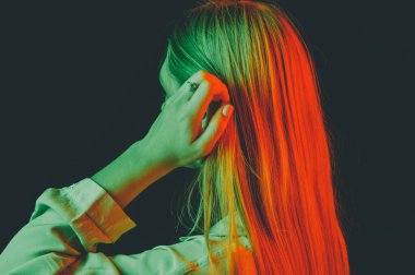 Güzel bir kadın modelin yaratıcı portresi. Stüdyoda turuncu ve yeşil ışık.