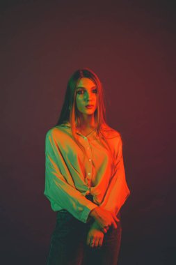 Güzel bir kadın modelin yaratıcı portresi. Stüdyoda turuncu ve yeşil ışık.