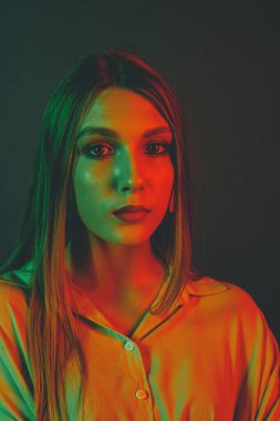 Güzel bir kadın modelin yaratıcı portresi. Stüdyoda turuncu ve yeşil ışık.