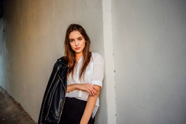 Siyah deri ceketli bir kız şehrin arka planında duruyor. Deri ceketli kız.