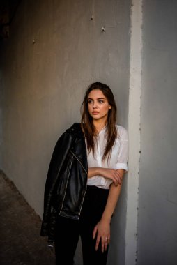 Siyah deri ceketli bir kız şehrin arka planında duruyor. Deri ceketli kız.