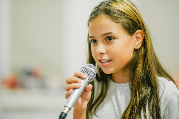 Young girl with microphone. Girl sings karaoke. A girl of 10-11 years old emotionally sings.