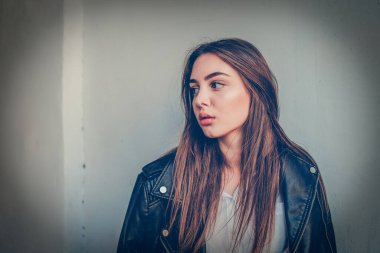 Siyah deri ceketli genç kız ayakta duruyor. Açık havada güzel bir esmerle çekilmiş bir dizi fotoğraf..