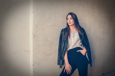 Siyah deri ceketli genç kız ayakta duruyor. Açık havada güzel bir esmerle çekilmiş bir dizi fotoğraf..