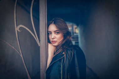 Siyah deri ceketli genç kız ayakta duruyor. Açık havada güzel bir esmerle çekilmiş bir dizi fotoğraf..