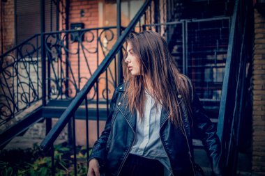 Siyah deri ceketli genç kız ayakta duruyor. Açık havada güzel bir esmerle çekilmiş bir dizi fotoğraf..