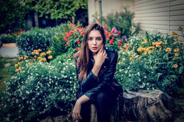 Siyah deri ceketli genç kız ayakta duruyor. Açık havada güzel bir esmerle çekilmiş bir dizi fotoğraf..