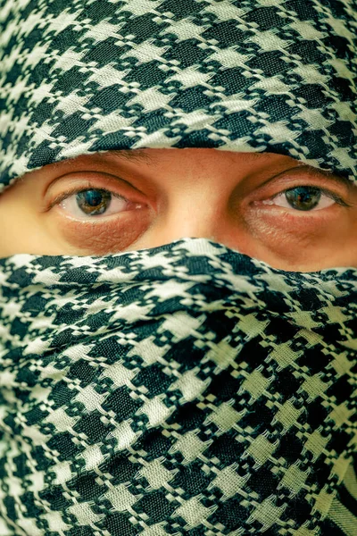 eyes of a man in arafatka. Man in arafatka. Portrait of a brunette man in a black and white arafatka