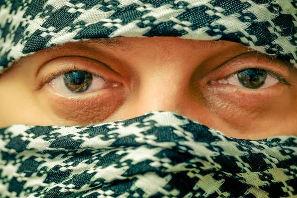 eyes of a man in arafatka. Man in arafatka. Portrait of a brunette man in a black and white arafatka