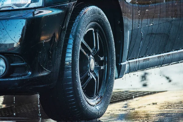 Arabayı yıka. Araba yıkamada siyah bir araba yıkamak.