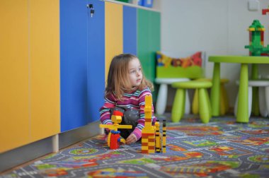 Oyuncaklı mutlu küçük kız. Oyun odasında oynayan küçük kız. Çocuk ve inşaatçı