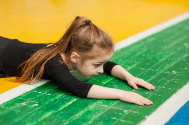 Küçük kız jimnastik yapıyor. Jimnastik salonundaki küçük kız. Spor salonundaki kız jimnastikçi. Spor sağlığı.