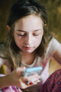 Pijamalı ergen kız telefona bakıyor. Yatağında akıllı telefonu olan genç bir kız.