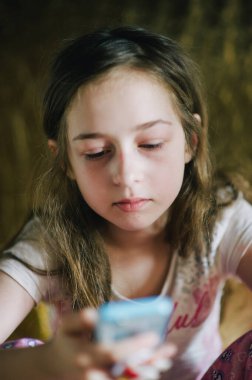 Pijamalı ergen kız telefona bakıyor. Yatağında akıllı telefonu olan genç bir kız.