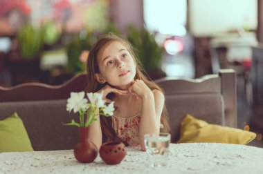 Sevimli küçük kız bardaktan su içiyor. Kafede bir bardak su içen küçük bir kız..