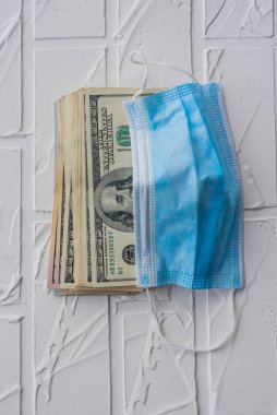 Para ve koruyucu tıbbi maske. Amerikan Doları banknotlarının yakın plan fotoğrafı. Makro çekim.