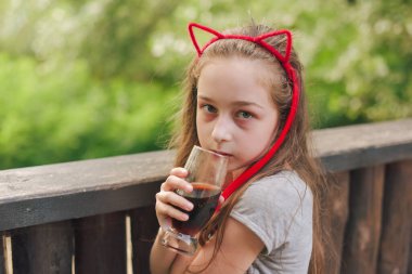 Lokantada içen sevimli, komik küçük kız. Kız bir yaz kafesinde bardaktan içiyor..