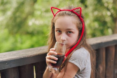 Lokantada içen sevimli, komik küçük kız. Kız bir yaz kafesinde bardaktan içiyor..