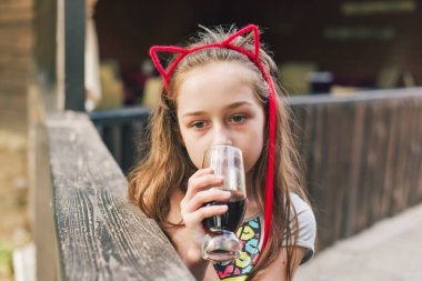 Lokantada içen sevimli, komik küçük kız. Kız bir yaz kafesinde bardaktan içiyor..